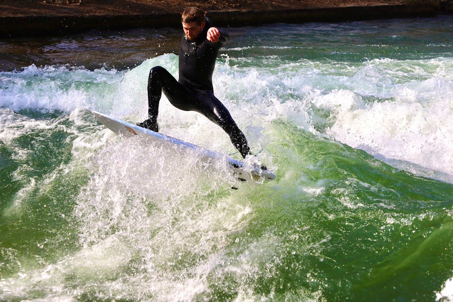 Man in a Wetsuit Surfing on Wavy, Foamy Water 