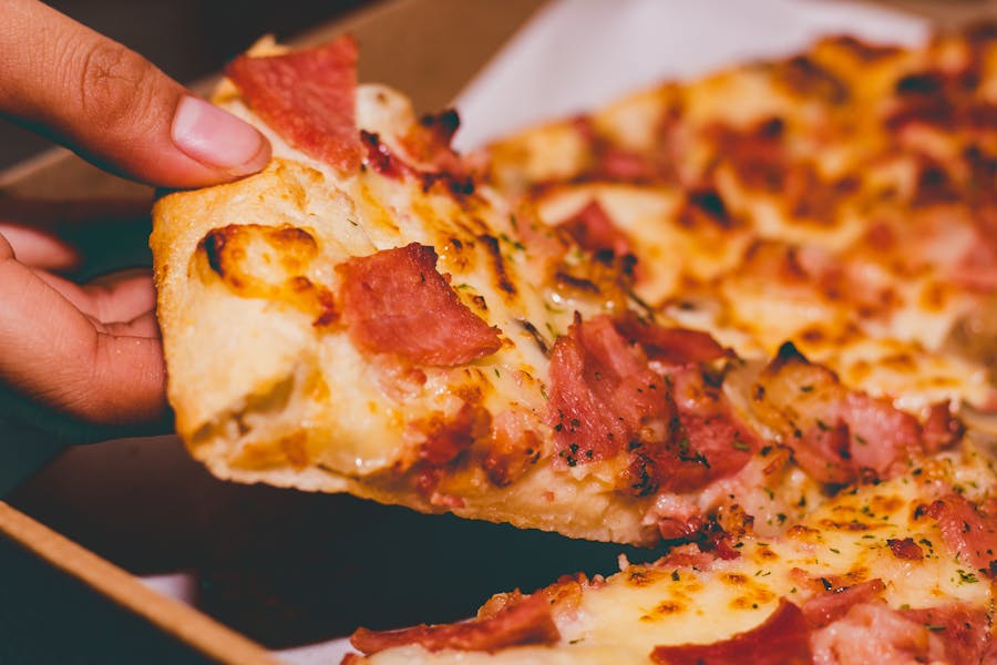 Close-Up Photo of Person Holding New York Pizza