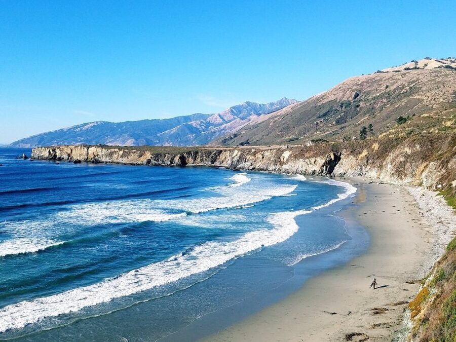 Waves roll onto the shore at Pfeiffer Big Sur State Park, framed by dramatic cliffs along the California coastline.
