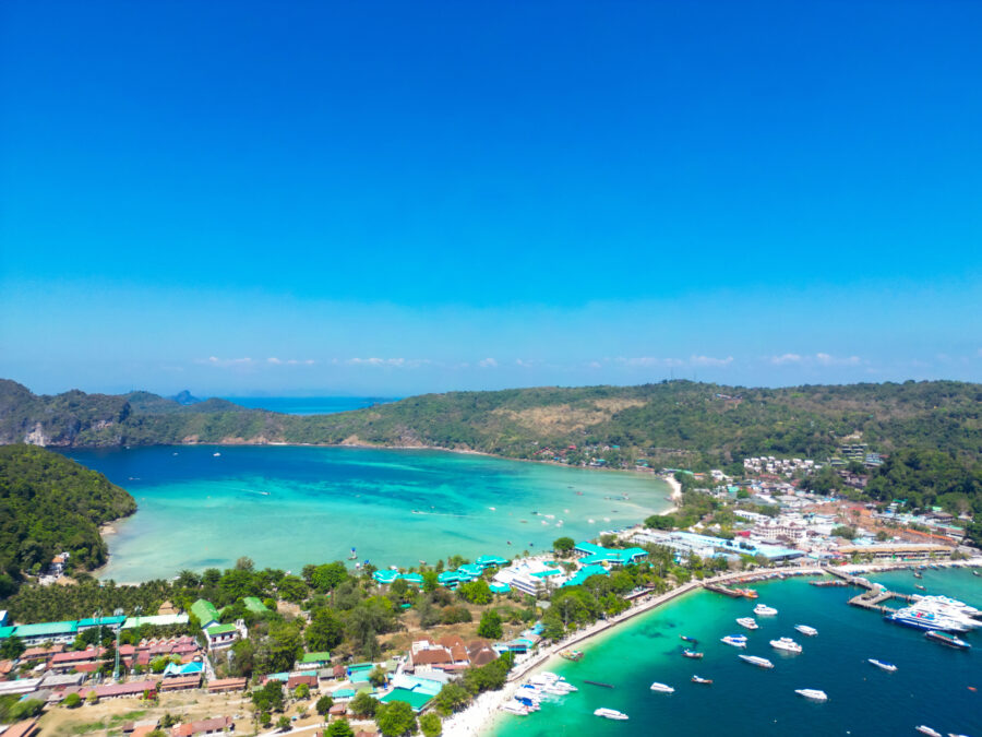 Aerial view of Phi Phi Island with a speedboat on turquoise waters, highlighting the tropical beauty and coastal landscape of Thailand