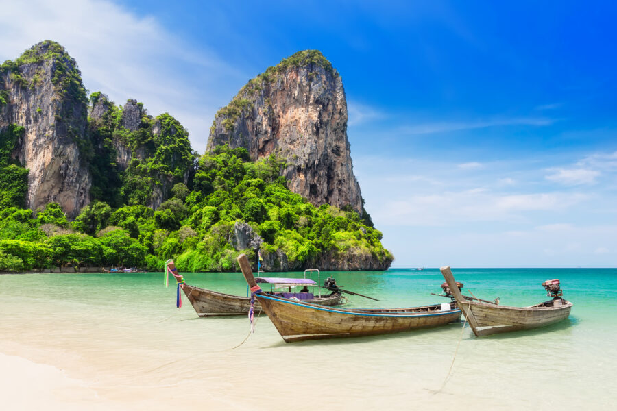 Wooden longtail boat on the sandy shores of Maya Bay, Phi Phi Islands, with lush greenery in the background