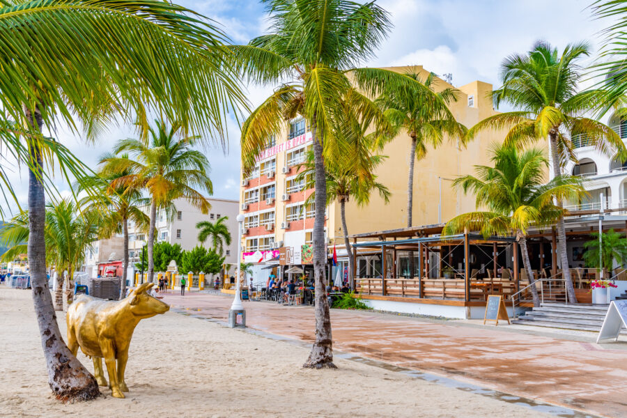 Waterfront view of Philipsburg, Sint Maarten, featuring colorful buildings along a paved boardwalk by the coast.