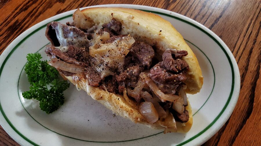 Delicious Philly cheesesteak sandwich served on a plate, topped with melted cheese and grilled onions.