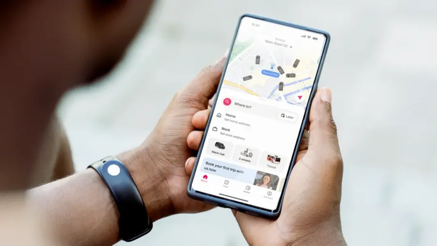 Hands holding smartphone showing ride-hailing map and booking interface.
