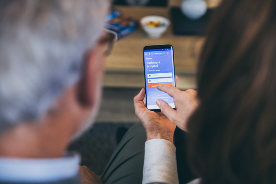 Couple booking Schiphol airport parking online via smartphone.