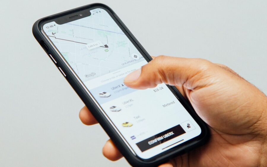 Person tapping smartphone to confirm a ride-hailing pickup on map with fare options.