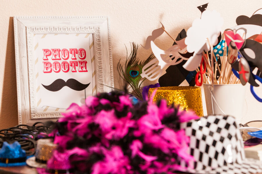 Table filled with colorful photobooth props, featuring a sign that highlights their purpose for guests
