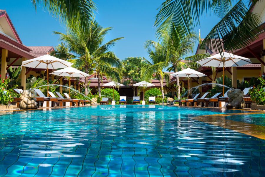 Beautiful tropical resort swimming pool in Phuket, Thailand, framed by palm trees and vibrant flowers