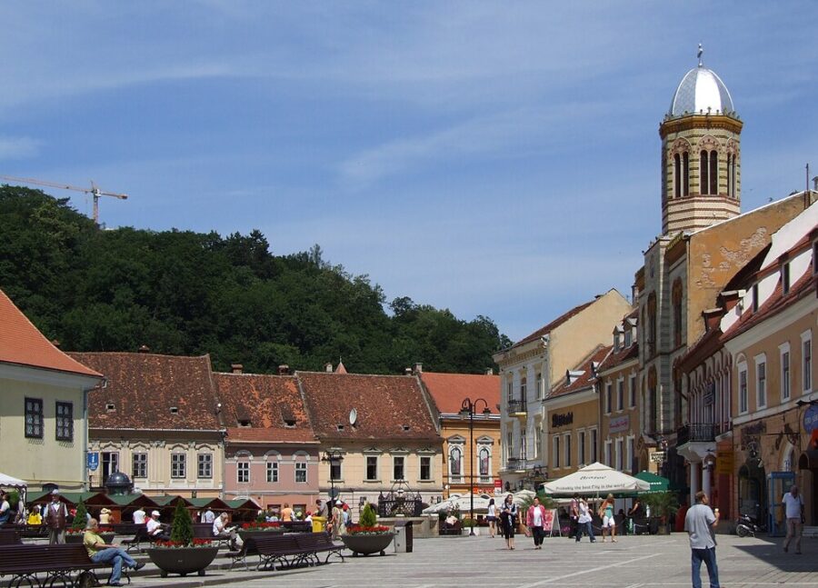 The clock tower of a large building in Piața Sfatului, Brașov, Romania, highlighting the city's rich history.