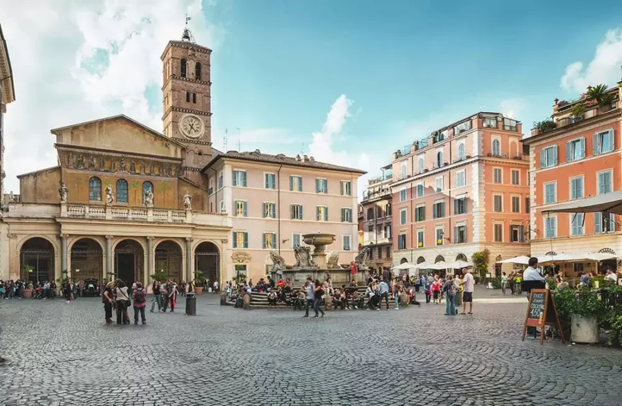 Historic Trastevere Rome piazza with fountain, cafes, cobblestone square and clock tower.