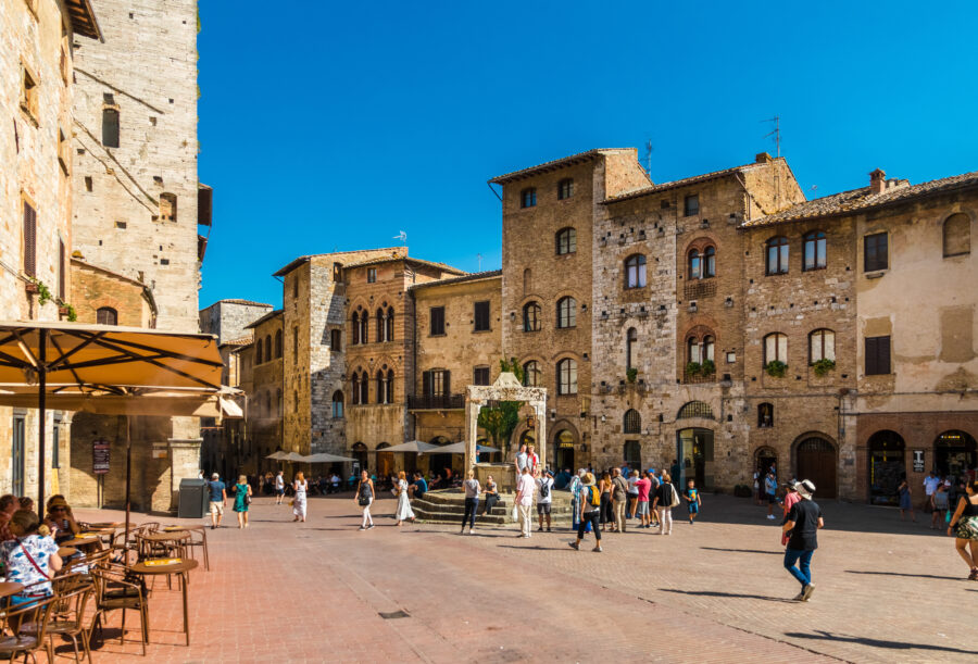 Scenic view of Piazza della Cisterna in San Gimignano, surrounded by medieval houses and featuring a travertine octagonal cistern