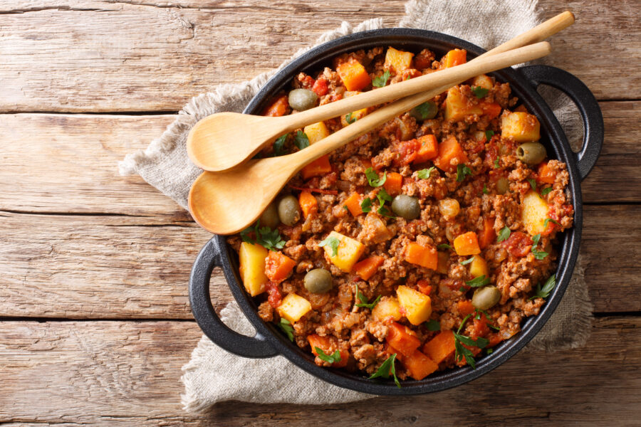 Close-up of delicious Picadillo in a frying pan, featuring ground beef, vegetables, raisins, and spices