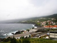Picturesque small town on Pico Island, Portugal, featuring a lighthouse perched on a hill overlooking the landscape.