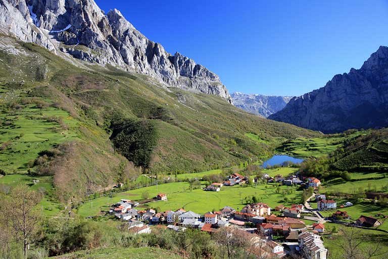 Small village in Picos de Europa National Park, Spain, set against a backdrop of green grass and majestic mountains.