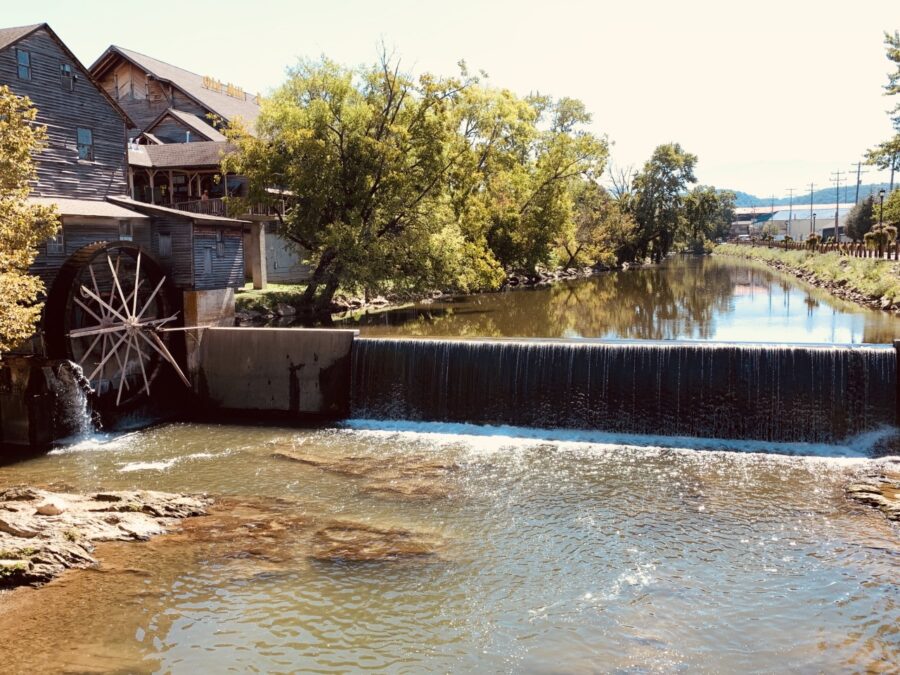 Scenic view of a river winding through the town of Pigeon Forge Mill, with charming structures along its banks.