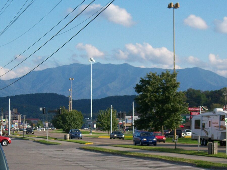 Car drives along Pigeon Forge Road with a mountain backdrop in the distance.