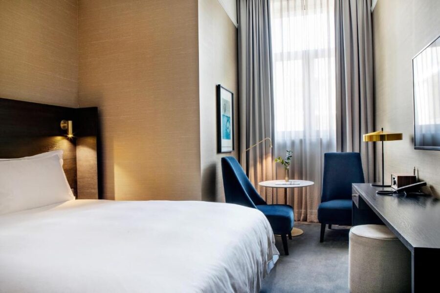 Interior of a hotel room at Pillows Grand Boutique Hotel Reylof Ghent, showcasing a bed, chair, and TV.
