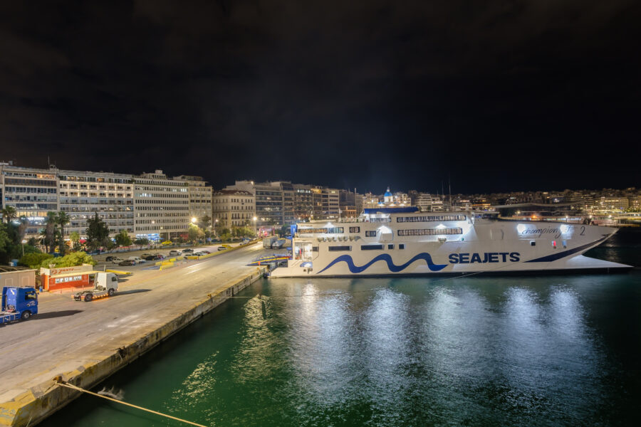 Night view of a Seajets ferry at the illuminated port of Piraeus, Greece, showcasing vibrant lights and calm waters