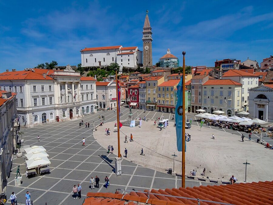 The bustling city square in Piran, Slovenia, featuring charming buildings and people enjoying the lively atmosphere.