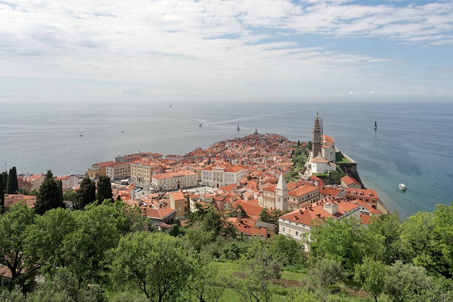 Scenic view of Piran, Slovenia, featuring a landscape filled with red roofs and the historic town walls.