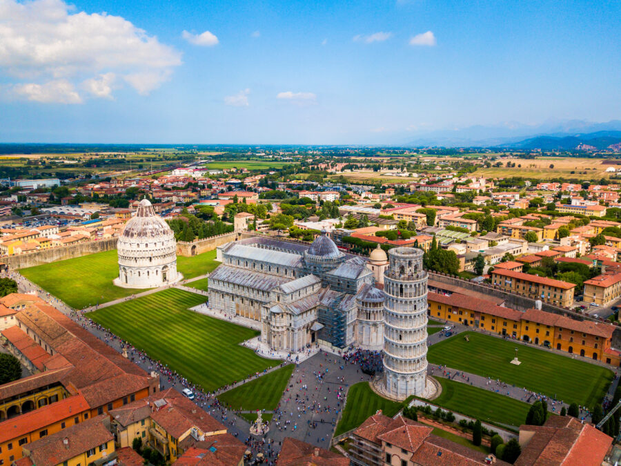 Cityscape of Pisa, Italy, featuring the iconic Leaning Tower and historic buildings under a clear blue sky
