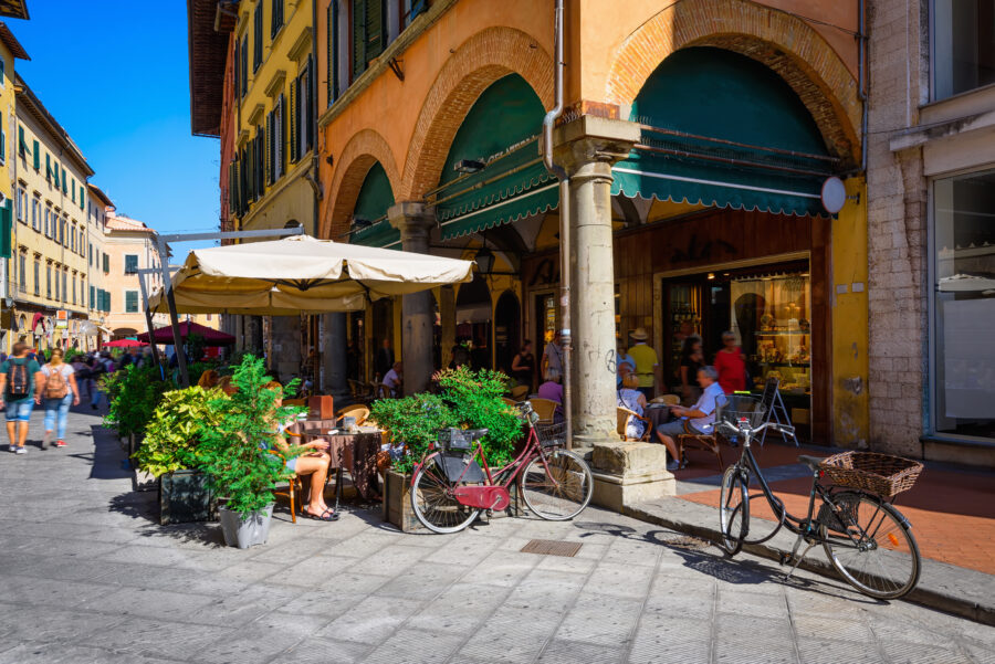 Narrow, cozy street in Pisa, Tuscany, featuring a charming cafe and traditional Italian architecture.