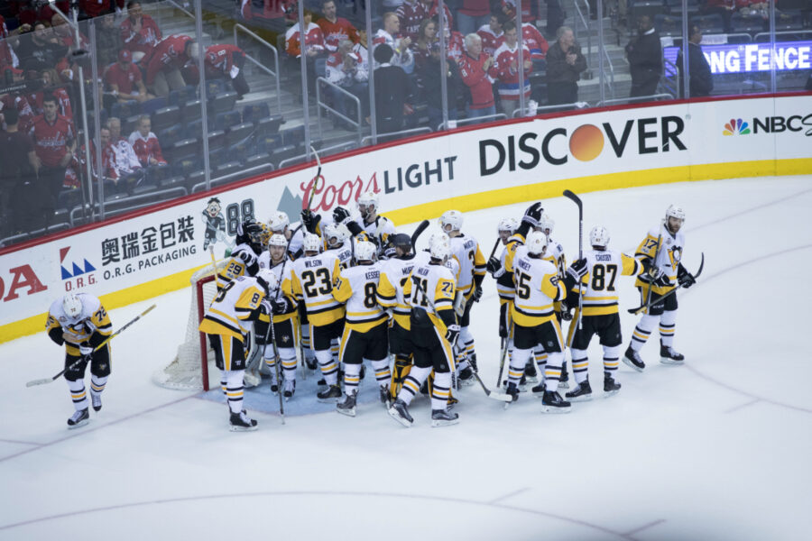 Pittsburgh Penguins players huddle together on the ice, focused and ready for the game action ahead.
