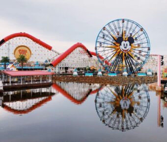 Pixar Pier Ferris wheel with Mickey Mouse face and roller coaster, vibrant amusement park atmosphere.