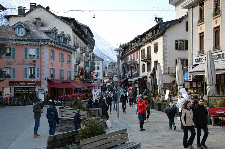 People walk together along a bustling street in Place Balmat, Chamonix-Mont-Blanc, enjoying the vibrant atmosphere.
