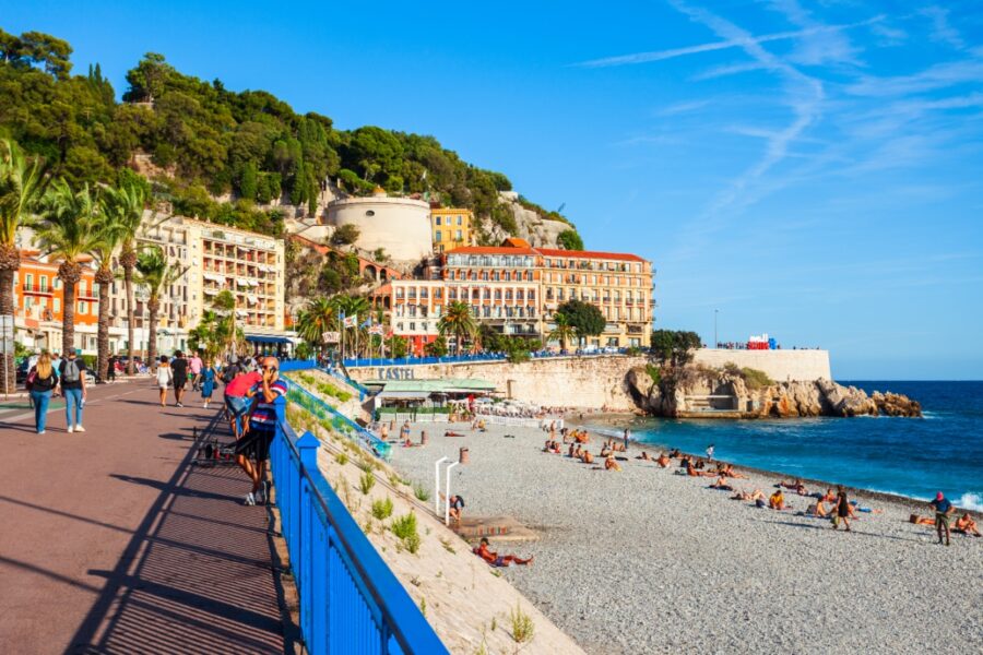 Scenic view of Plage Blue Beach in Nice, France, showcasing vibrant blue waters, sandy beach, and sunbathers relaxing