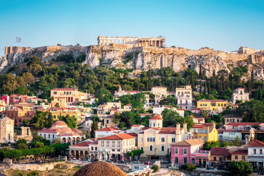 Scenic image of Plaka neighborhood featuring traditional architecture, with the iconic Acropolis towering above