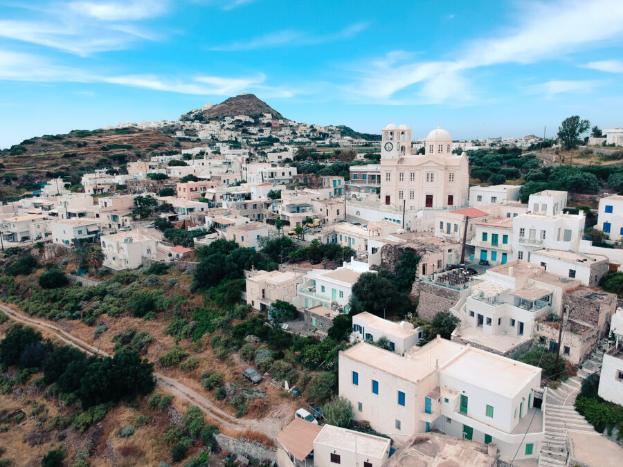 Aerial view of Plaka village on Milos island during a summer sunset, showcasing the vibrant colors of the sky and rooftops