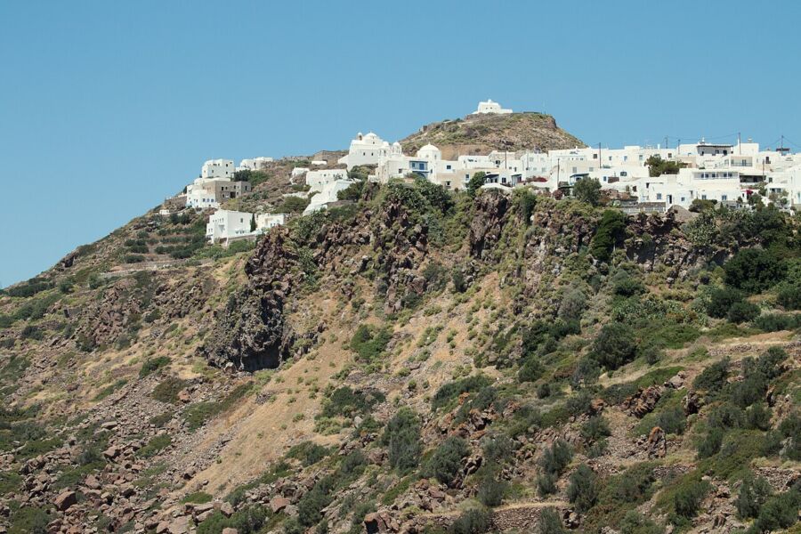Prominent white building on a hillside in Plaka, Milos, Greece, offering a scenic view of the surrounding landscape.