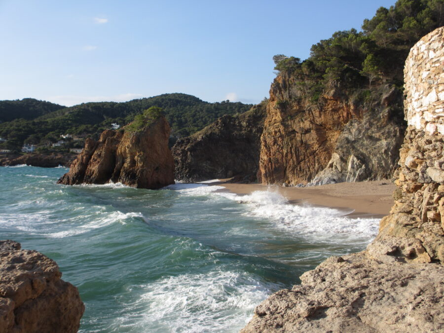 Blue water at Platja de Pals beach, Costa Brava, Spain, reflecting the clear sky and surrounding landscape.