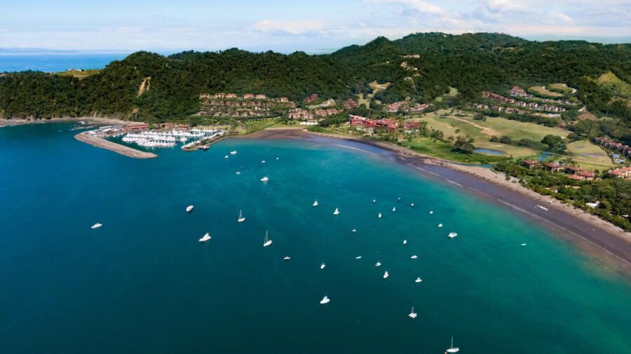 Scenic view of Playa Herradura, Costa Rica, featuring golden sands, turquoise waters, and lush green hills in the background