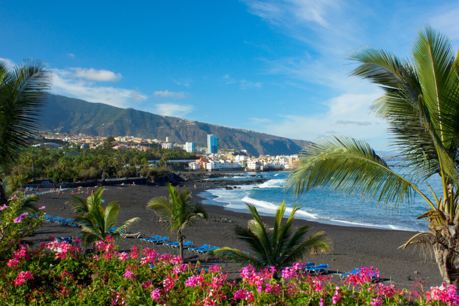 Playa Jardin in Tenerife, Spain, features black sand beaches, lush gardens, and scenic ocean views under a clear blue sky