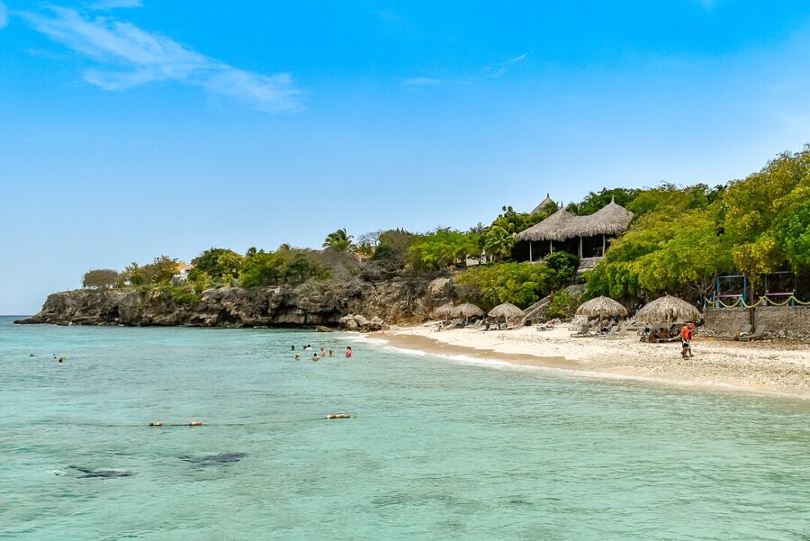 Playa Kalki Beach in Westpunt, Curacao, showcasing a beach hut and visitors relaxing on the sandy shore.
