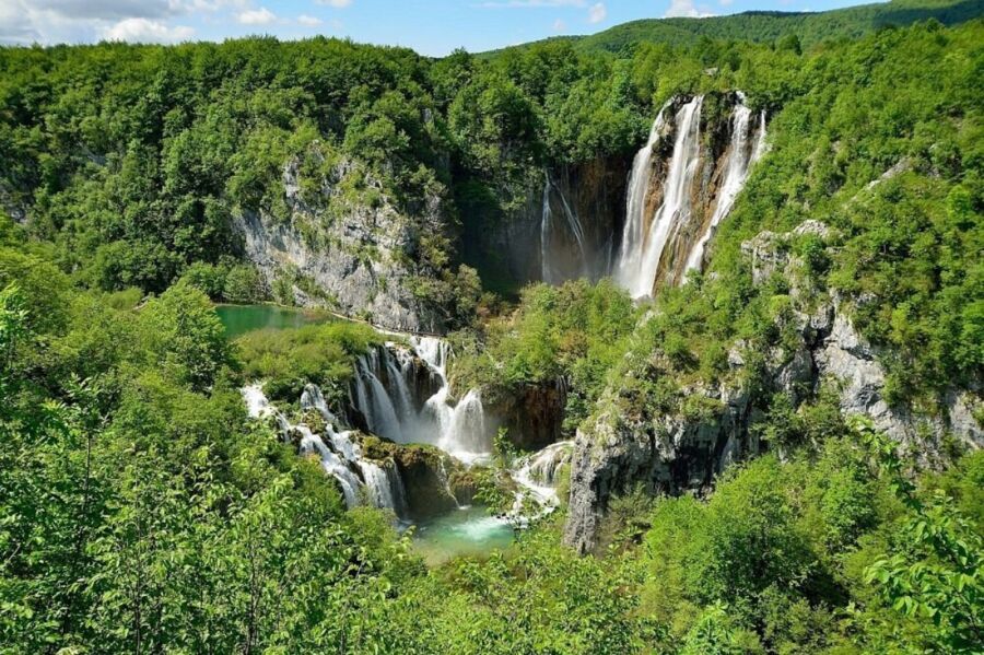 Scenic view of waterfalls cascading through lush greenery in Plitvice Lakes National Park, Croatia.