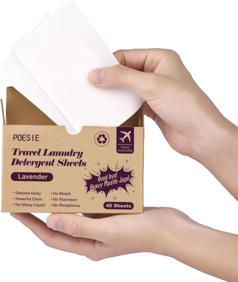 Hands holding a box of lavender-scented travel laundry detergent sheets, displaying eco-friendly icons and text like “Goodbye heavy plastic jugs.”