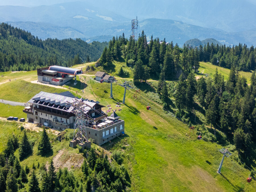 Aerial view of Poiana Brașov, Romania, featuring lush forests and the scenic Carpathian mountains surrounding the ski resort.