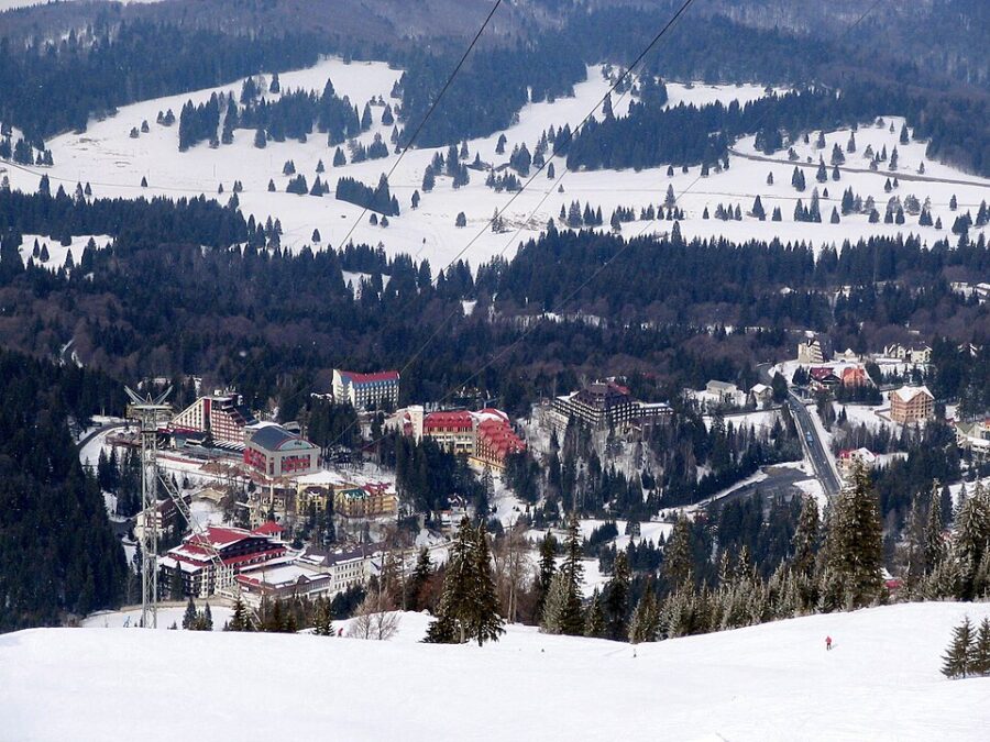 Ski lift in mid-air at Poiana-Brasov, offering a panoramic view of the snowy slopes and surrounding forest.