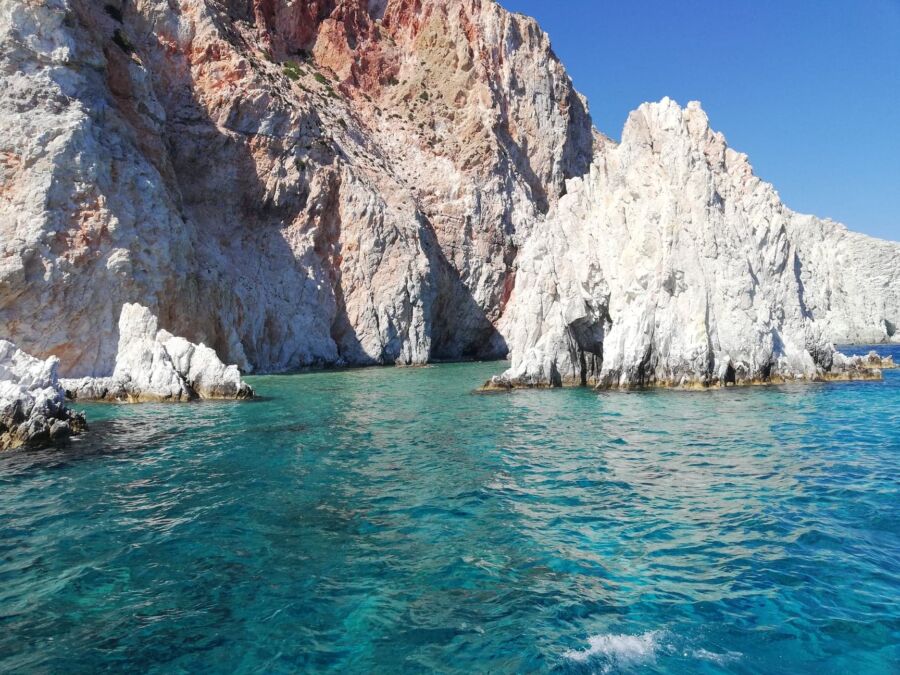 Rocky cliffs of Polyaigos Island, Greece, showcasing rugged terrain and coastal beauty against a clear blue sky.