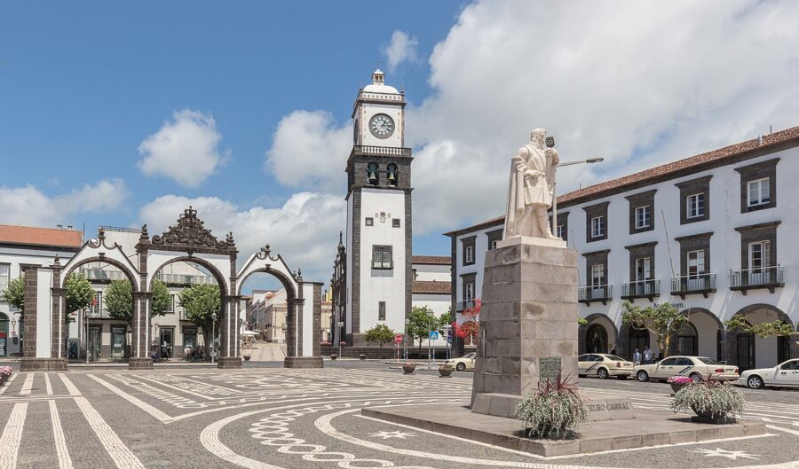 In Plaza de Gonçalo Velho, a statue of a man is featured with a clock tower behind it in Ponta Delgada, São Miguel.