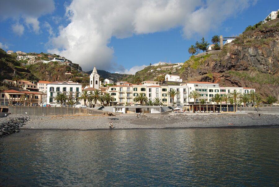 Ppicturesque landscape of Ponta do Sol, Madeira, showcasing a vast water body, beach, and surrounding buildings.

