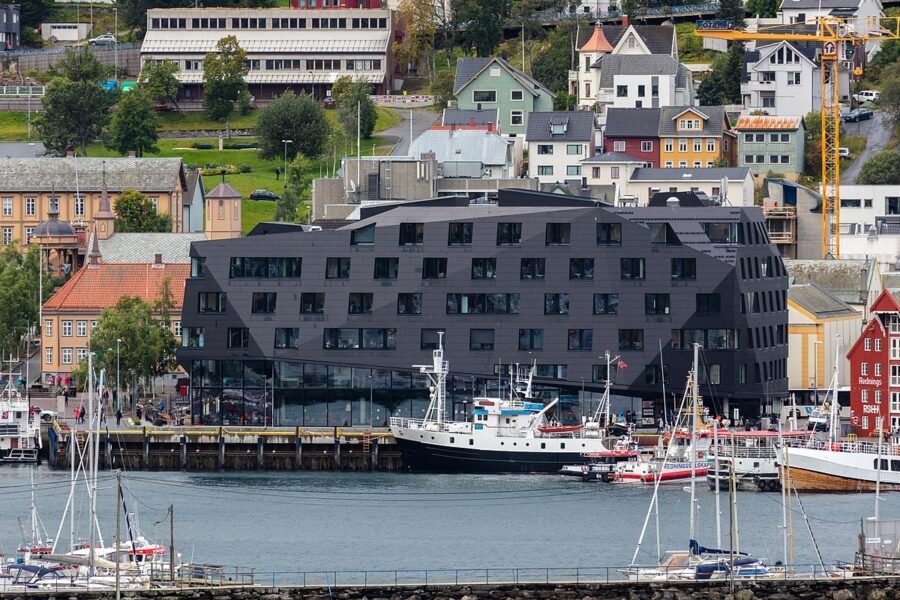 Prominent structure with a black roof at the Port of Tromso, Norway, set against a backdrop of scenic landscapes.
