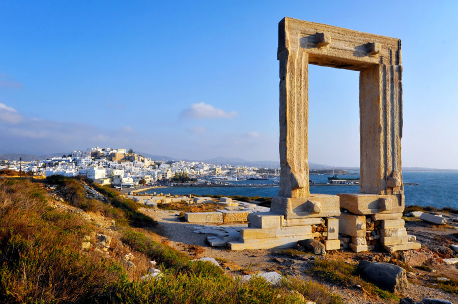 The iconic Portara, a monumental marble doorway, is situated on Naxos Island, Greece, with a scenic coastal backdrop.