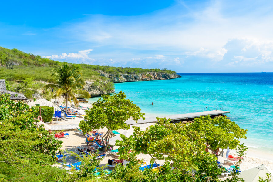 Porto Marie beach features white sand, a blue sky, and crystal-clear water in Curacao, Netherlands Antilles, Caribbean.
