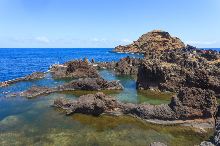 Scenic view of Porto Moniz, Madeira, showcasing natural volcanic swimming pools and rugged coastal cliffs.
