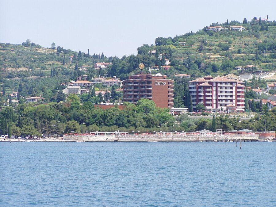 Large building situated on a hillside in Portorož, Slovenia, surrounded by greenery and overlooking the landscape.