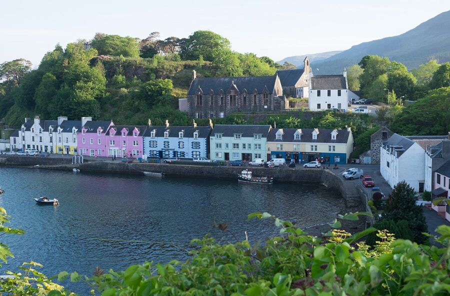 Colorful houses line the water at Portree Harbour Front, Isle of Skye, creating a picturesque village scene.
